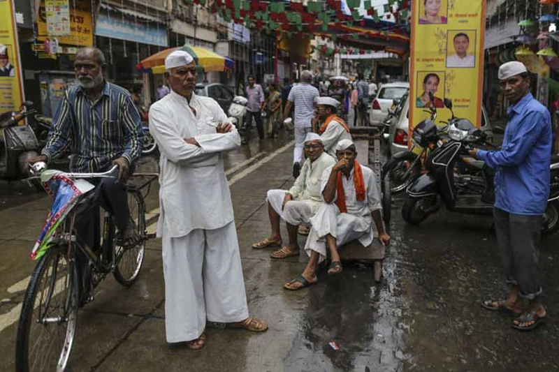 Gatescene fra Mumbai. Til venstre en mann på sykkel og i midten flere menn som ser i kamera.
